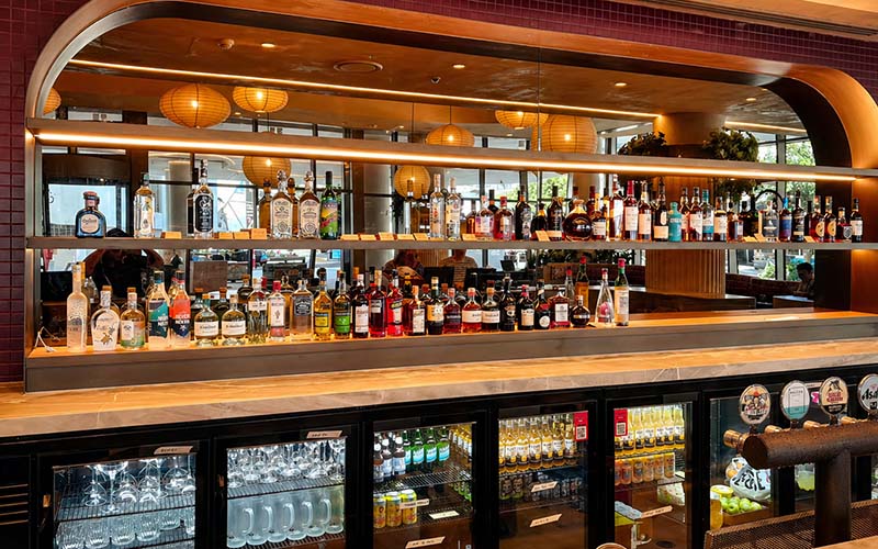 Coloured glass splashback behind bar shelving