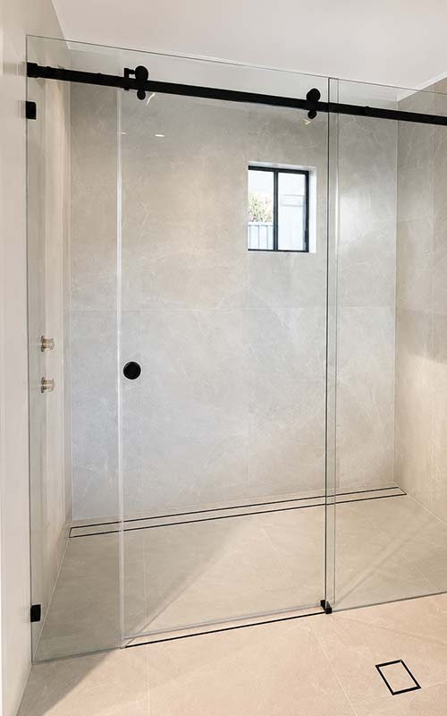 Frameless glass shower screen in tiled bathroom